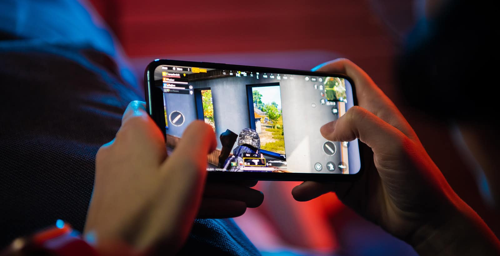 Celulares Gamer Muchacho jugando en su celular dos manos un juego de shooting